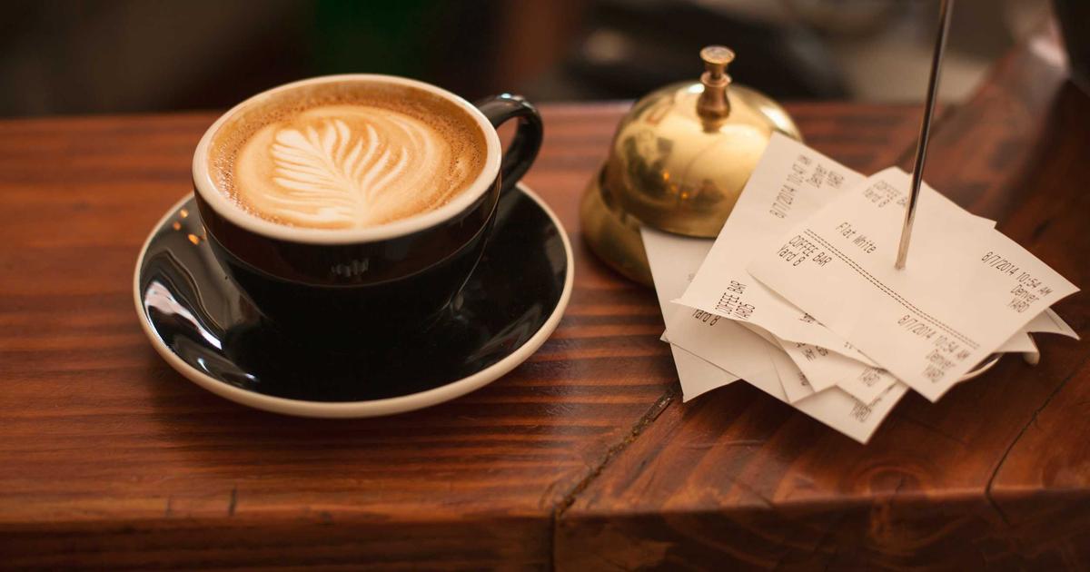 Coffee and a stack of receipts on a table, representing financial paperwork