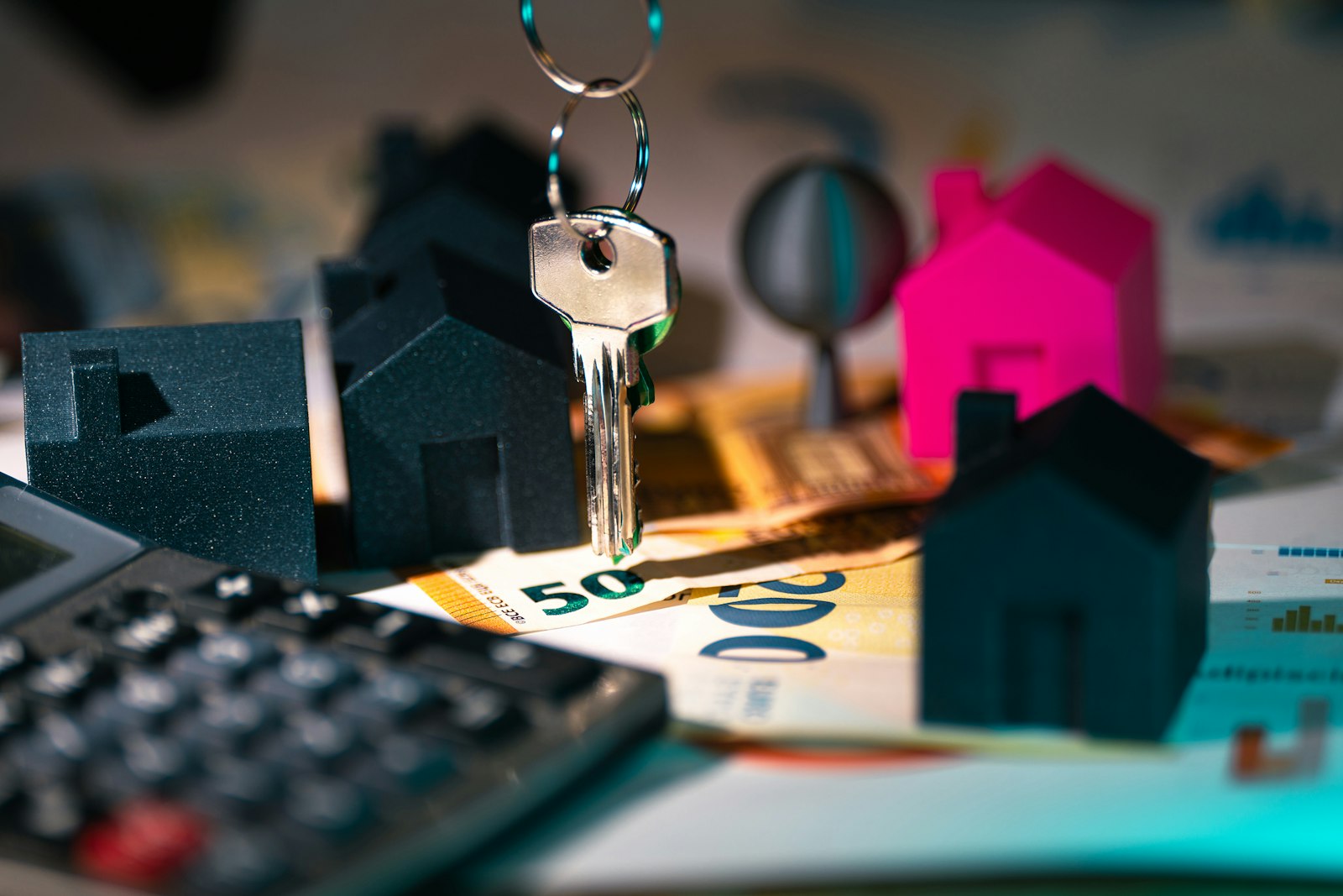 A house model, a key, and a calculator on a table of financial documents